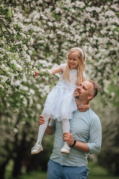 Happy father lifting daughter in blooming spring orchard
