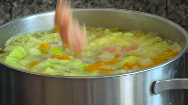 Timelapse of cooking a homemade vegetable soup with meat dumplings and fresh dill in a stainless steel pot on a stove.