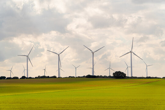 Wind turbine farm over green field under cloudy sky