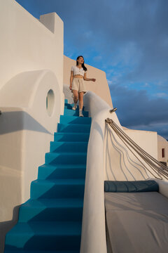 Asian woman on blue stairs at luxury hotel in Santorini
