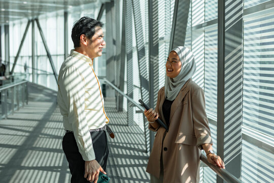 Business colleagues talking in sunlit modern office corridor