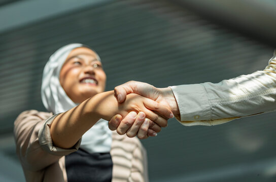 Business handshake with smiling Muslim woman in hijab