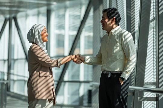 Business partners shaking hands in modern office corridor