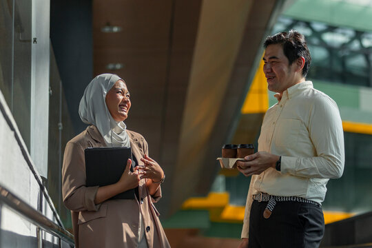 Coworkers chatting with coffee in modern transit station