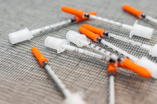 Insulin syringes with orange caps on woven surface