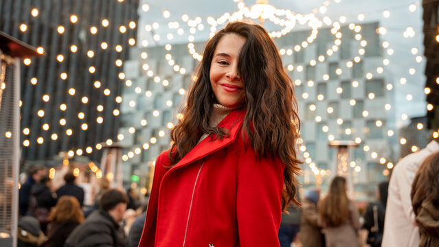 Smiling woman in red coat at Christmas market lights