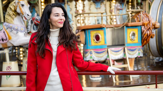 Woman in red coat at Christmas market fairground carousel