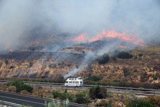 An ambulance races along a highway as a fast approaching wildfire threatens the vicinity of Los Gallardos in Almeria province in southern Spain amid an urgent emergency evacuation and rescue response.