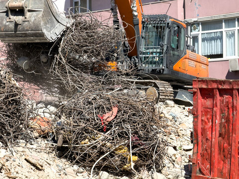 Excavator sorting rebar and rubble during building demolition