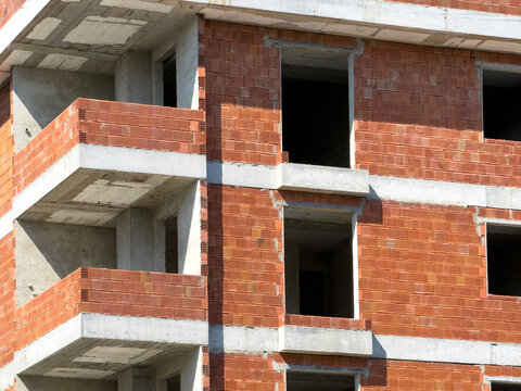 Unfinished brick apartment block facade with concrete slabs