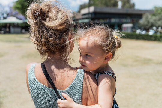 Grandmother carries granddaughter outdoors on sunny day