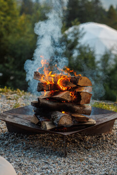 Cozy evening campfire with burning firewood at an eco hotel campsite.