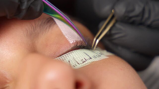 Beautician applying eyelash extensions in beauty salon