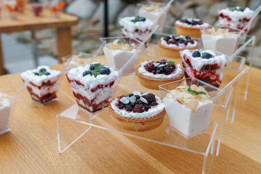 Catering buffet table with sweet mini desserts in cups and refreshing cocktails.