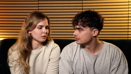 Obraz premium Young couple discussing serious relationship problems while sitting on a couch at home