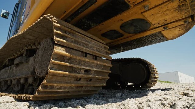 Heavy machinery rolls over rough terrain under bright blue sky