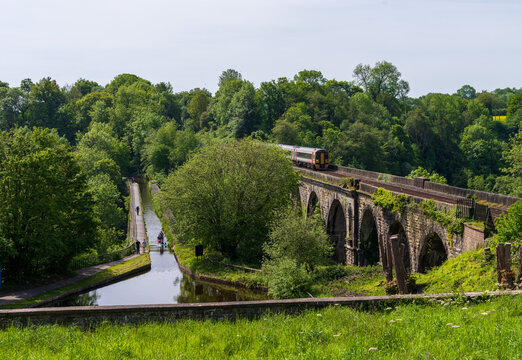 Historic Chirk Aqueduct and railway viaduct in Shropshire, UK by Thomas Telford with local diesel train and canoe or kayaker on Llangollen Canal