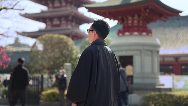 Unrecognized young smiling Latino man calm, curious while taking a photo with his smartphone at Sensoji Temple in Asakusa Tokyo Japan, iconic historic landmark with pagoda, wearing traditional kimono