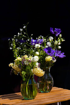 Colourful beautiful flowers in bloom inside glass vases on wooden table interior