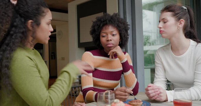 Diverse women pals at table by sliding doors right woman talking comforting central stirring spoon