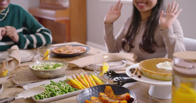 Diverse women joining hands at table, African American woman pouring water from pitcher for meal