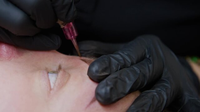 Experience the artistry of eyebrow tattooing as a skilled professional shapes and defines brows using a specialized machine. The procedure showcases vibrant pigments and precise techniques