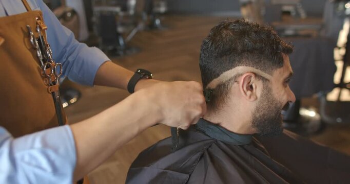 African American barber placing black cape on client, clipping nape into fade at shop, copy space