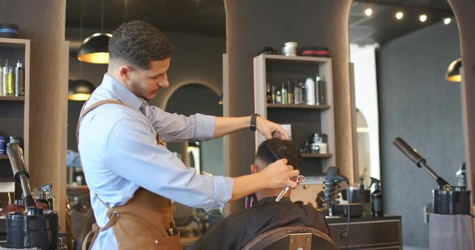 African American barber and client sitting cutting trimming hair for fade at salon with trimmer