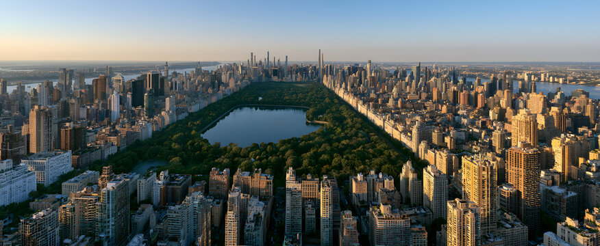 A view of Central Park from above, in Manhattan, New York. The park is encircled by tall buildings. A stunning sight of the Jacqueline Kennedy Onassis Reservoir is visible in the park's center.