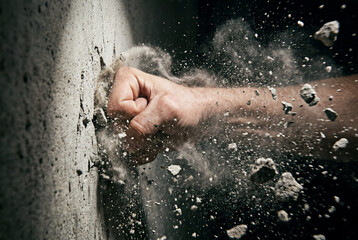 Fototapeta premium Powerful fist punching concrete wall with flying debris