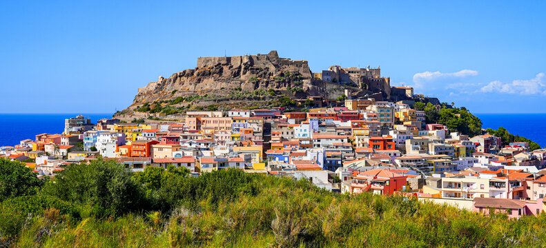 Historic castle ruins and colorful terraced houses in the hilltop town of Castelsardo, Sardinia, Italy