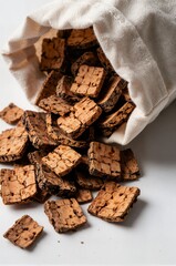 Fototapeta premium Natural cork square tiles spilling from canvas sack on white background ideal for sustainable eco materials branding packaging and texture design template