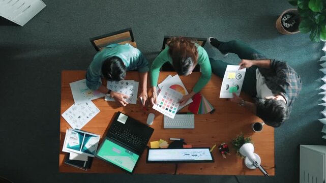 Top view of project manager writing idea while team joining meeting and talking about idea. Professional designer design logo while looking at color palette and writing idea down in paper. Symposium.