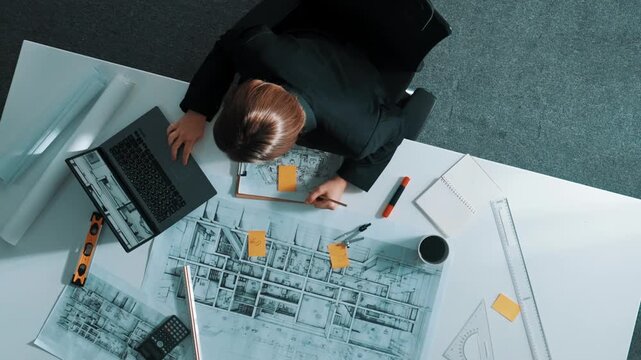 Top view of civil engineer using ruler and equipment to measure blueprint. Architect working while working on laptop with sticky notes and calculator to design building construction. Alimentation.