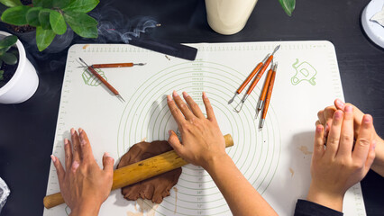 Rolling out brown modeling clay with a wooden rolling pin © Дарʼя Сидорова