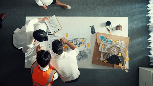 Top down view of skilled architect engineer working together to plan building at meeting table. Aerial view of smart interior design looking at project plan while check mistake point. Alimentation.
