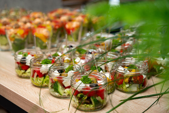 Buffet table with colorful assorted salads and appetizers in transparent glass bowls for catering event background