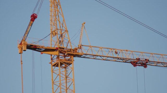 Crane operation above incomplete structure under cloudy sky. Urban development scene showing cranes and concrete core against overcast sky mood