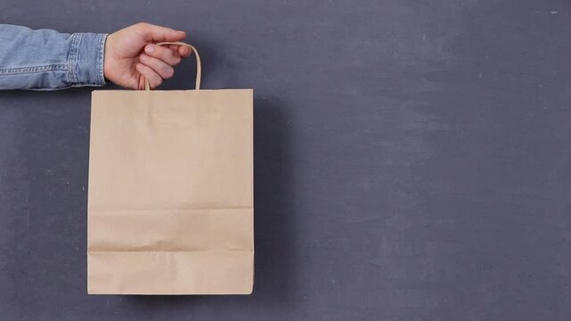 Hand holds paper bag against dark surface