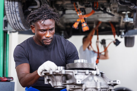 Professional electric vehicle technician performing a detailed inspection of an electric drive unit in a modern EV service workshop. 