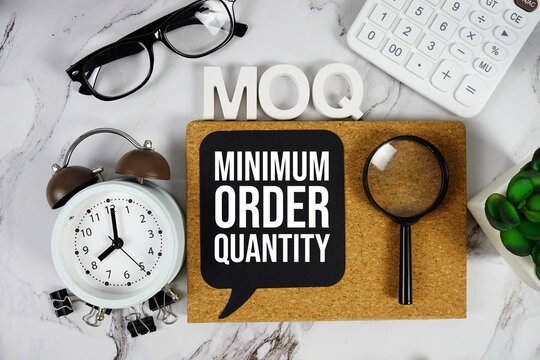 MOQ - Minimum Order Quantity acronym with calculator, alarm clock and magnifying glass, Business concept background