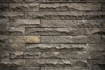 Dark stone texture showing detailed rough surface of rectangular brick cladding used for architectural backgrounds and modern wall designs. © Okta