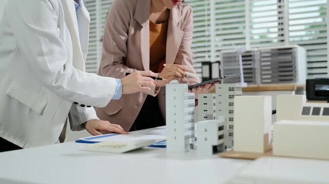 Business professionals review a residential building model during an architecture meeting design and investment.