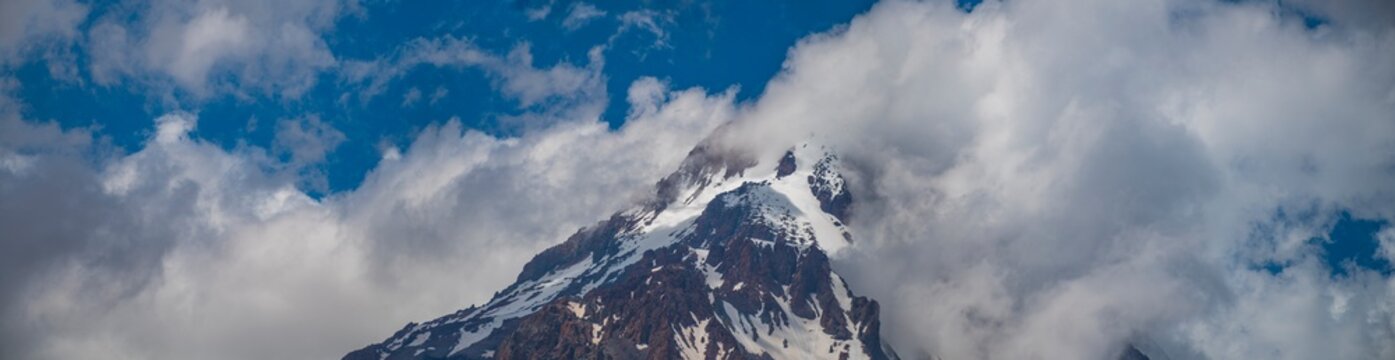 Majestic Mount Kazbek snowy peak breaking through clouds in Georgia with copy space