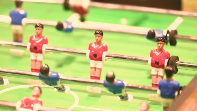 Close up of foosball players during table football match showing spinning handles, miniature teams and competitive indoor game atmosphere in social recreation space