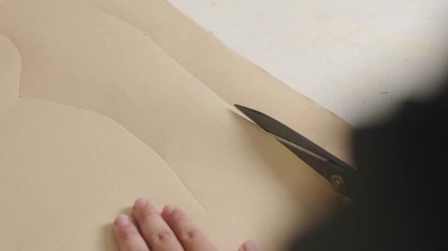Fashion designer cutting garment pattern pieces from fabric for custom clothing production