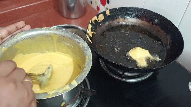 Close up of frying traditional Indian batata vada or aloo bonda pakora in hot oil