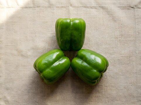 Fresh green bell peppers stacked together. Vibrant organic vegetables in natural light. Healthy produce for cooking and nutrition content.