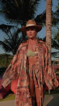 Stylish woman in bikini and lightweight beach kimono  at luxury resort.