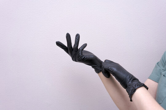Hands in Black Nitrile Gloves Reaching against a Grey Wall